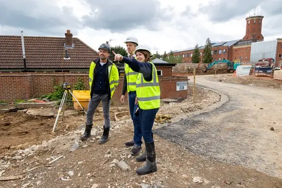 3 people in high visability vests on construction site pointing